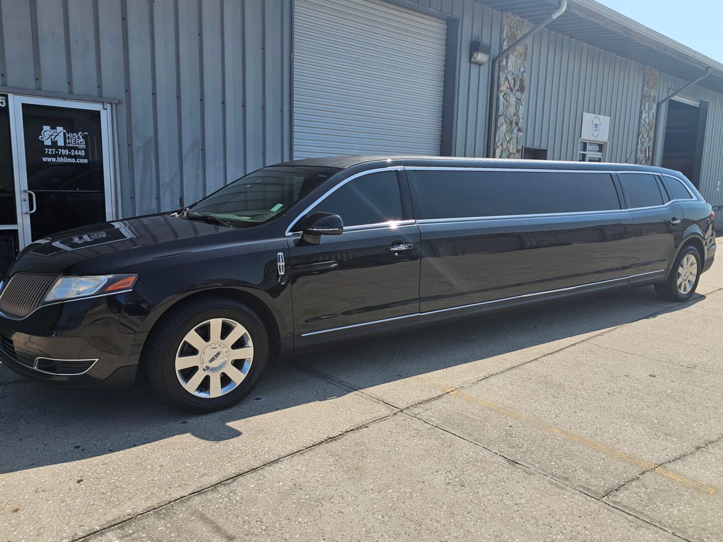 Long black limousine by warehouse