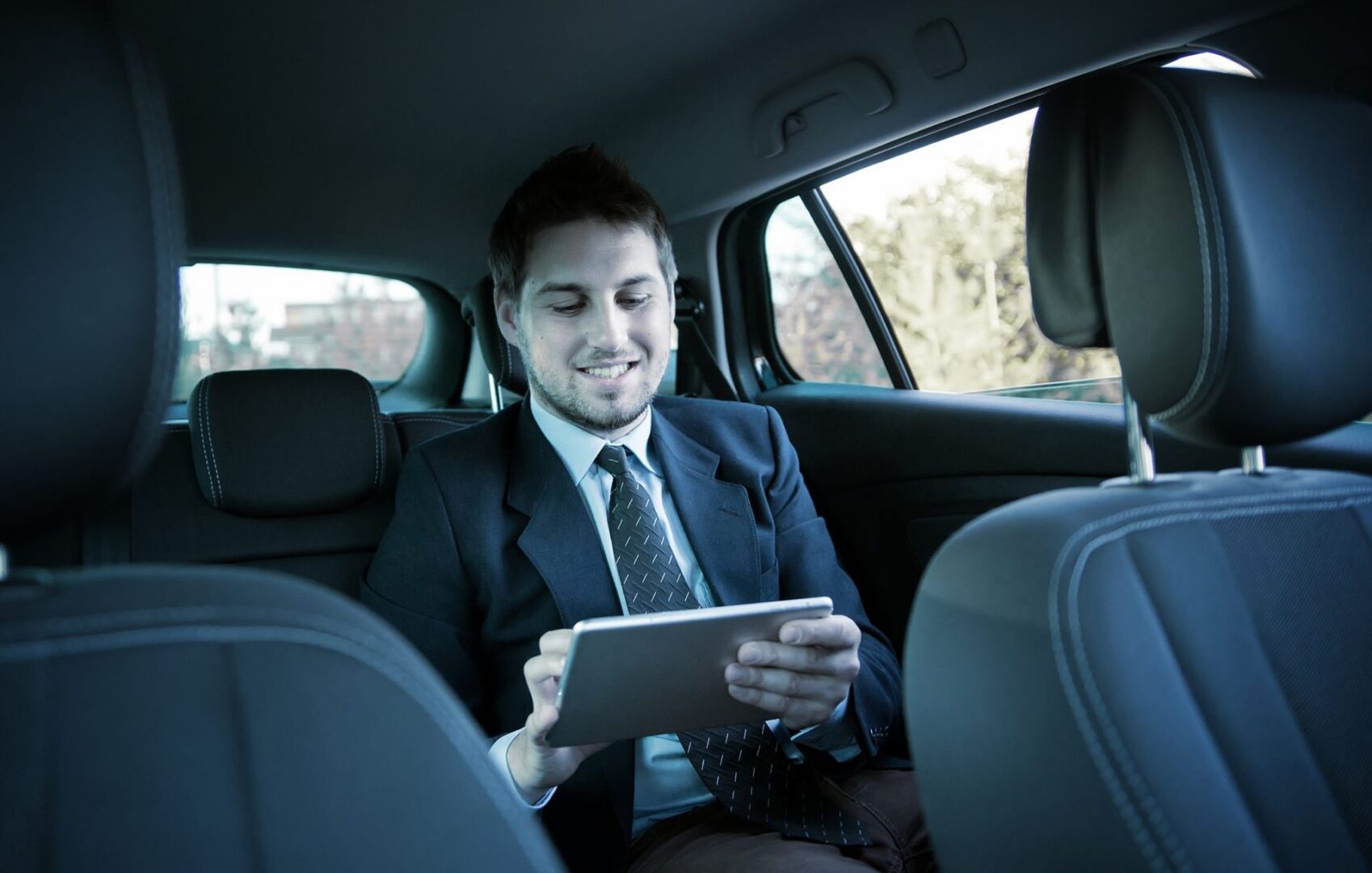 Man in suit using tablet in car