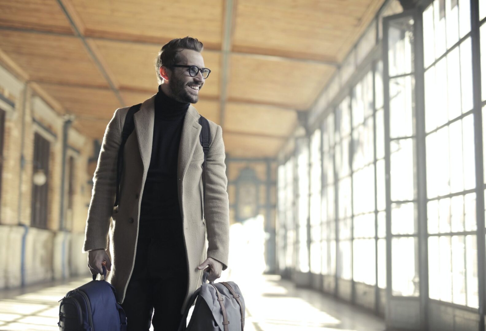 Traveler in coat holding bags indoors