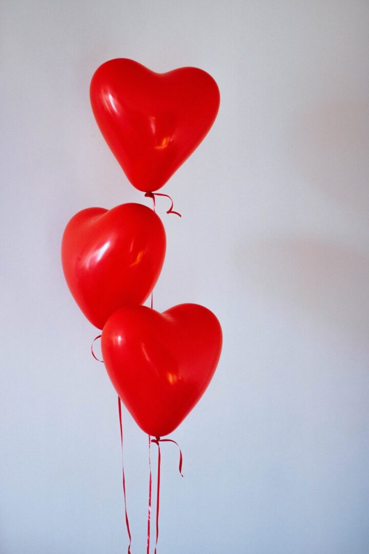 Red heart-shaped balloons against white background