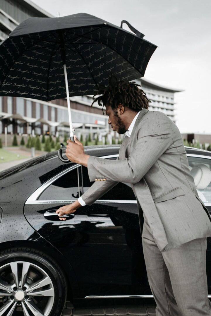Professional with umbrella near luxury vehicle