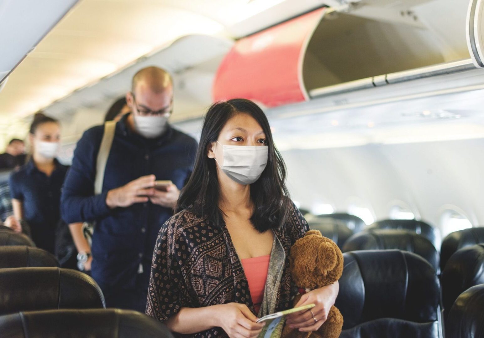 Woman holding teddy bear on plane