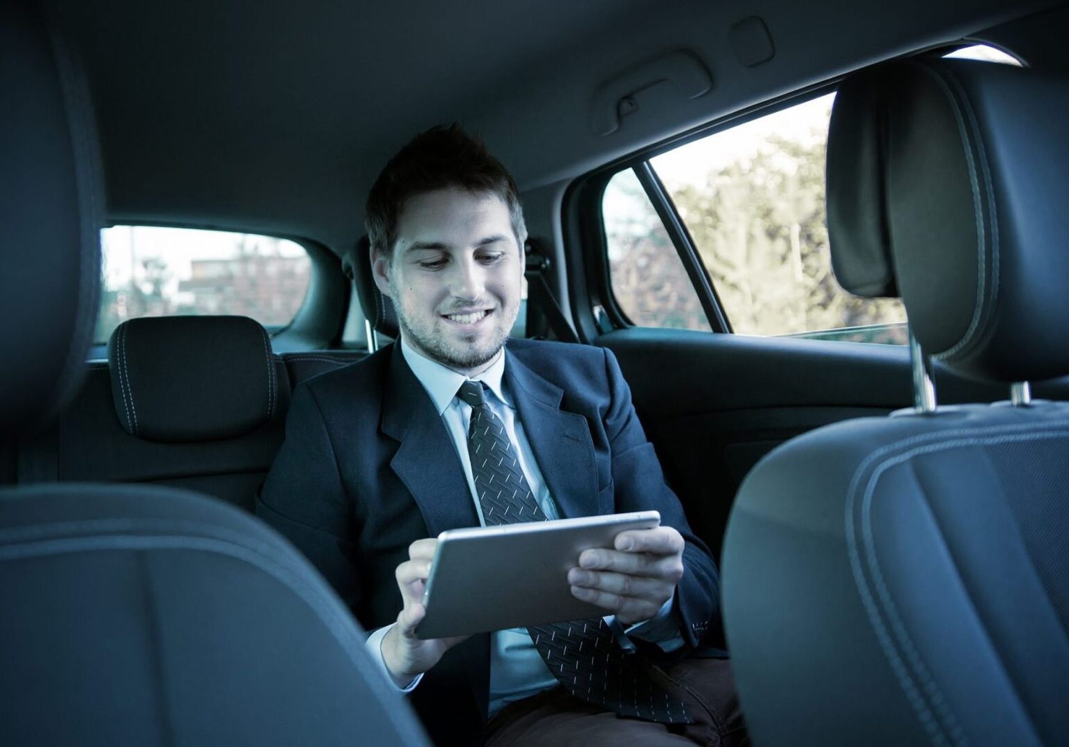 Man in suit using tablet in car