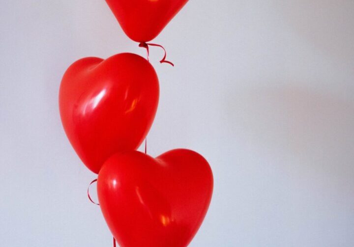 Red heart-shaped balloons against white background