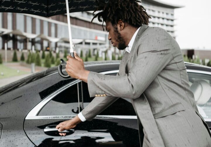 Professional with umbrella near luxury vehicle